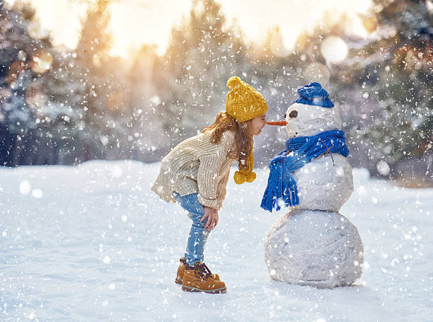 Girl in a yellow hat building a snowman