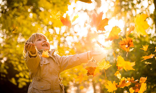 Happy child playing in golden fall leaves